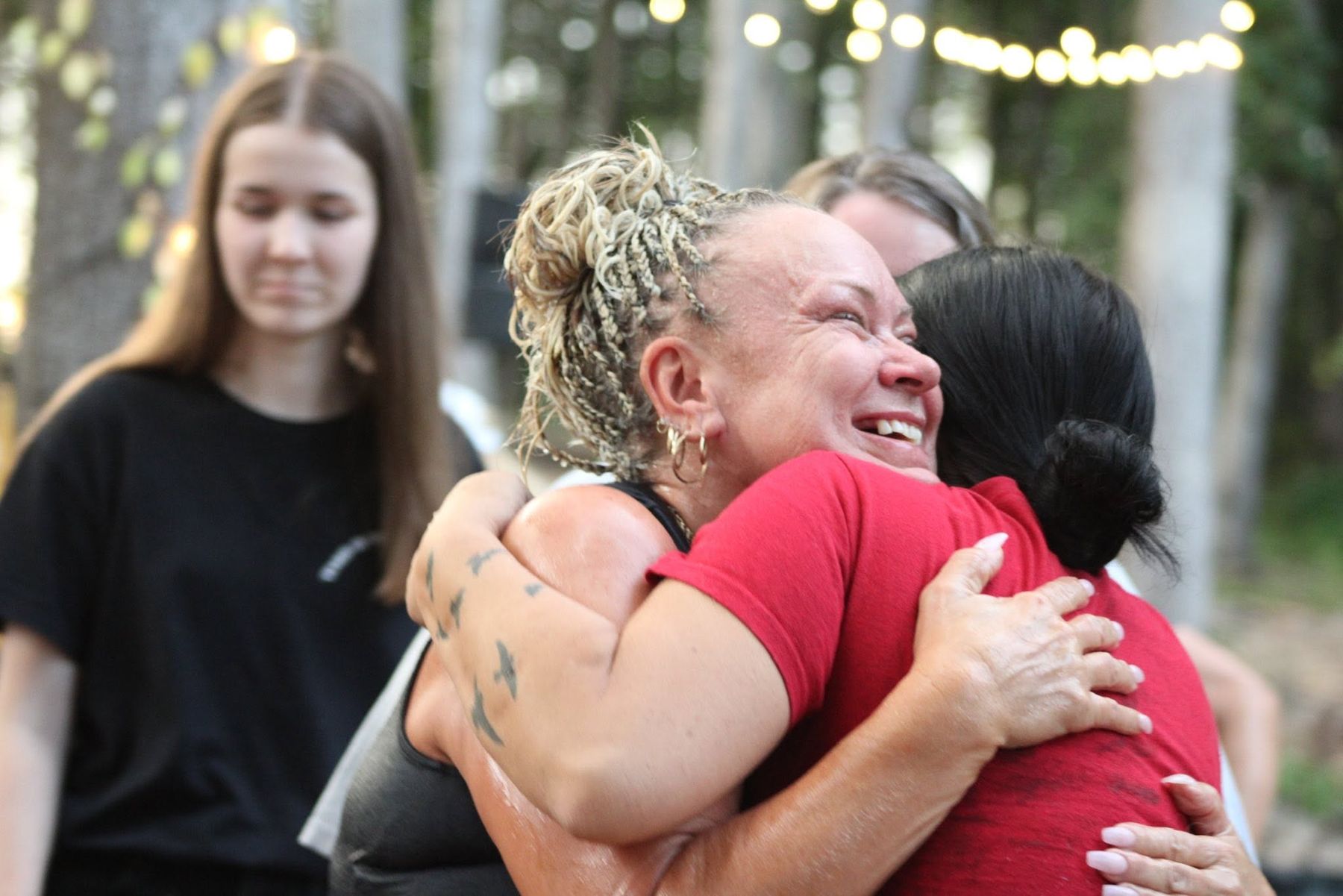 Two women hugging at an outdoor gathering